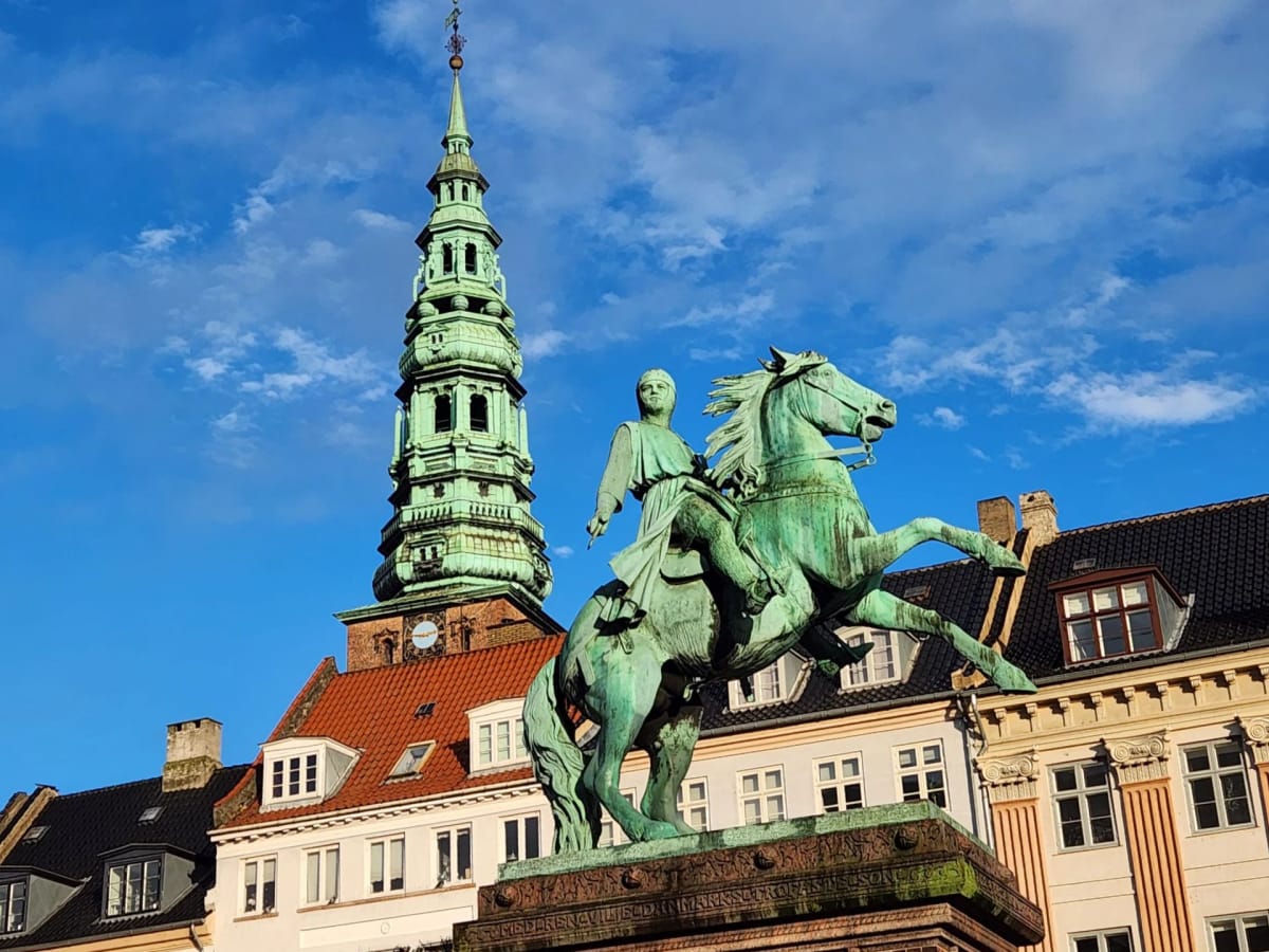 The spire of Nikolaj Church behind the statue of Bishop Absalon at Højbro Plads, Copenhagen