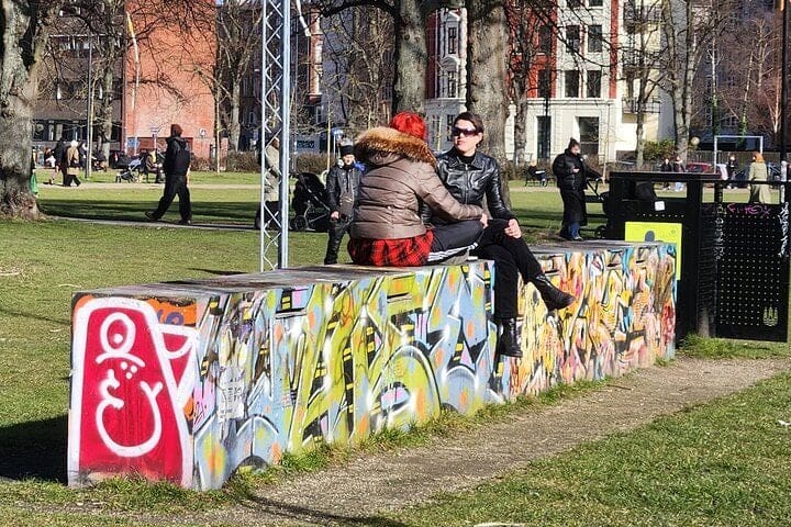 Locals sitting on a graffiti-covered bench in a Nørrebro park